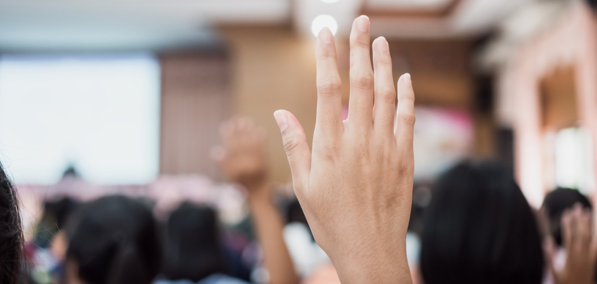 Zuhörer oder Studenten, die bei einer Konferenz die Hand heben, um eine Frage zu beantworten