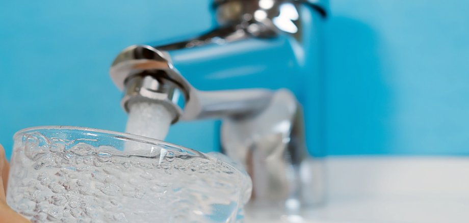 Trinkwasser läuft in ein Glas unter einem Wasserhahn Trinkwasser läuft in ein Glas unter einem Wasserhahn